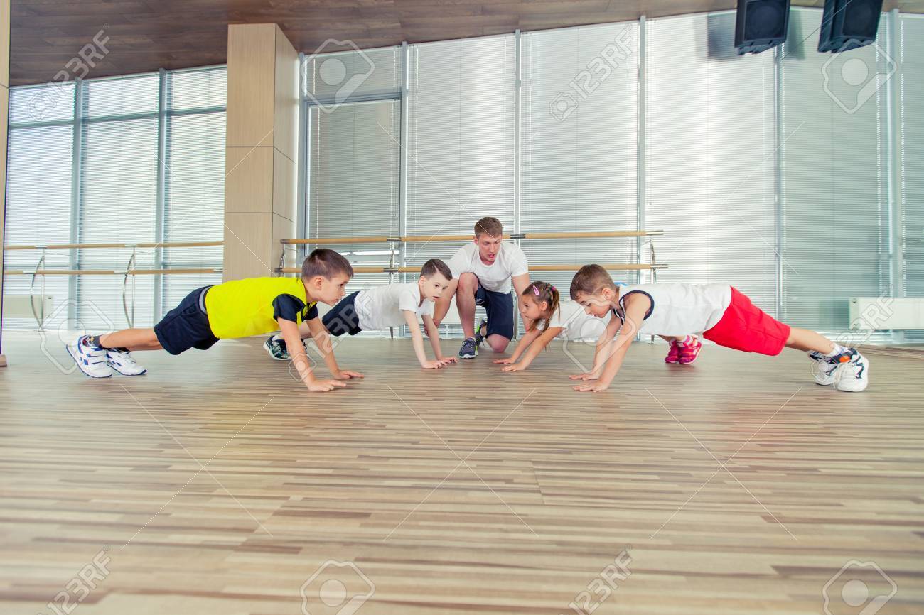 Group of children doing kids gymnastics in gym with nursery teacher. - 65293813 Group of children doing kids gymnastics in gym with nursery teacher. - 65293813