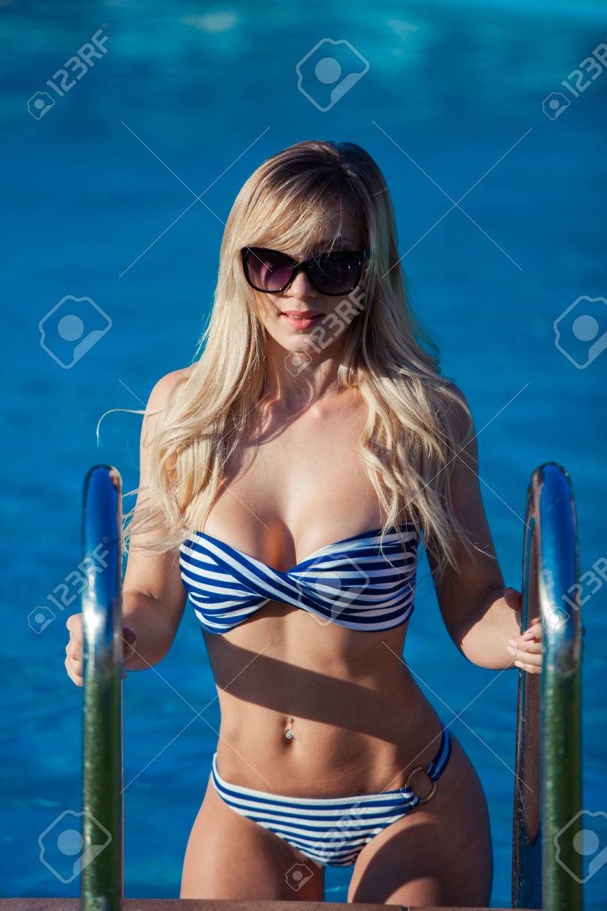 かわいい水着で美しい若い女性はスイミング プールの階段に立っています 彼女はとても素晴らしい笑顔です の写真素材 画像素材 Image