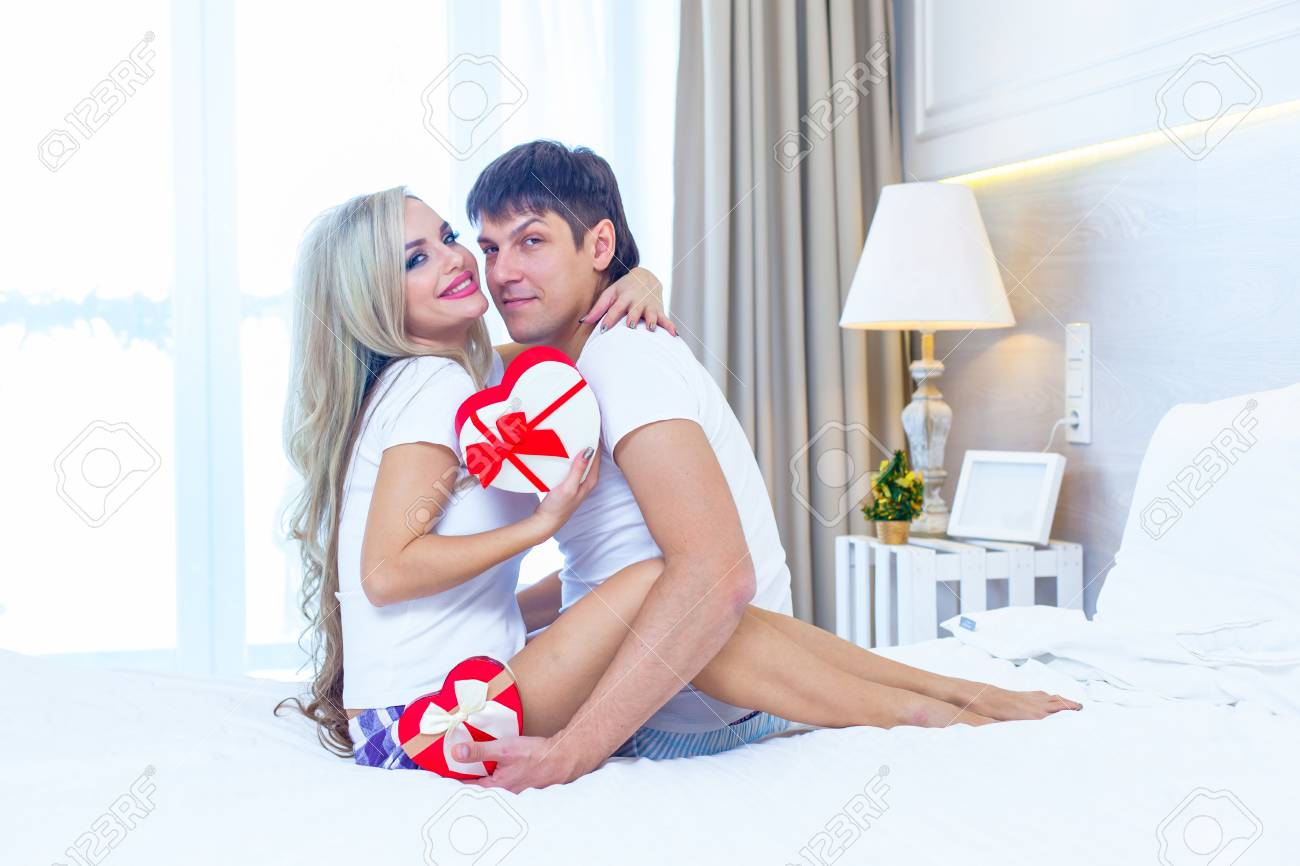 Jeune Couple Heureux Couche Dans Son Lit Homme Hispanique Donner Femme Surprise Enveloppe Present Avec Ruban Anniversaire Celebration Amoureux Dans Chambre Banque D Images Et Photos Libres De Droits Image