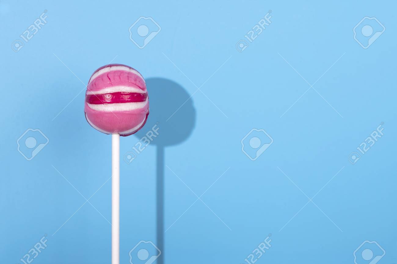 pink lolipop candy with shadow on pastel blue background minimal