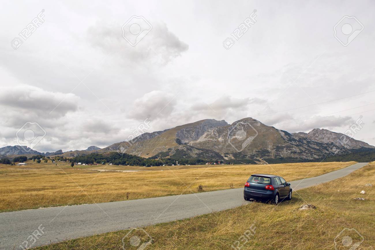 旅行者と車は秋にモンテネグロのザブラクの黄色いフィールドの道端に立っています の写真素材 画像素材 Image