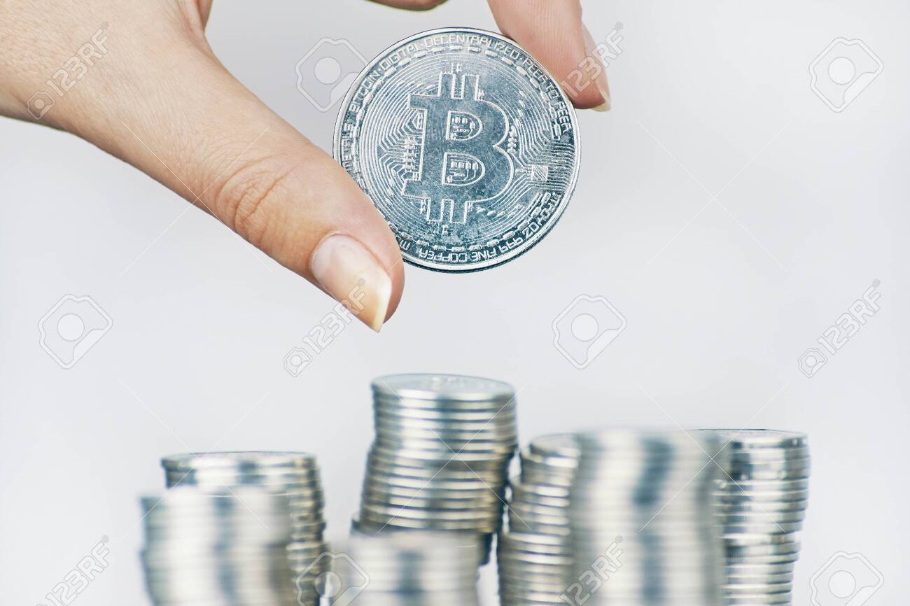 여자는 많은 국제 화폐 동전 위에 비트코인 동전 은비트 동전을 보유하고 있습니다. 로열티 무료 사진, 그림, 이미지 그리고  스톡포토그래피. Image 135136036