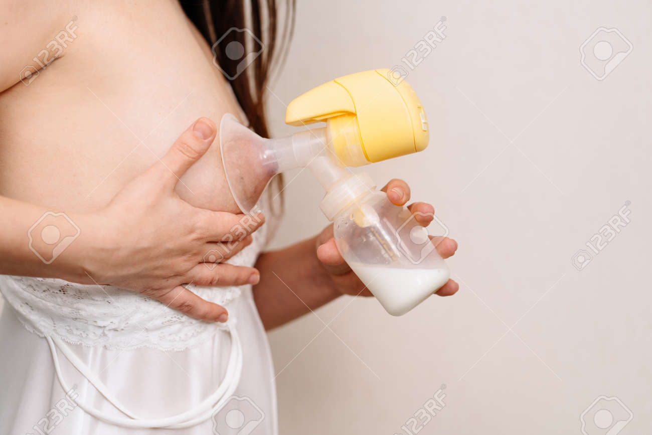 女性は白い背景に搾乳器を使用しています。碑文のためのスペース。母乳を搾り出すための装置。新生児を持つ母親のための商品やアクセサリー。母乳育児。の写真素材・画像素材  Image 181576800