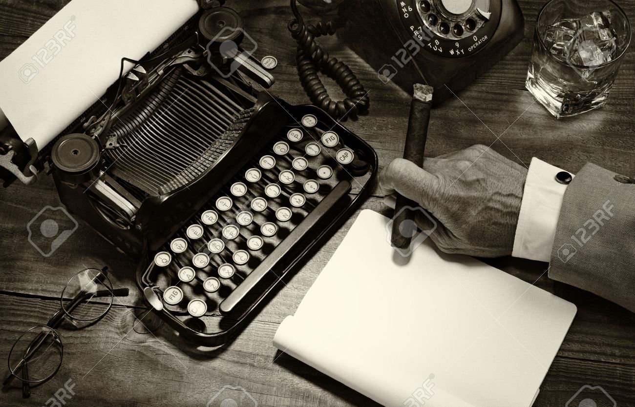 Closeup of a writer at his desk with a typewriter, rotary telephone, glass of whiskey and a cigar. Black and white toned image for a vintage feel. Only the mans hand holding a cigar is shown. - 36499264 Closeup of a writer at his desk with a typewriter, rotary telephone, glass of whiskey and a cigar. Black and white toned image for a vintage feel. Only the mans hand holding a cigar is shown. - 36499264