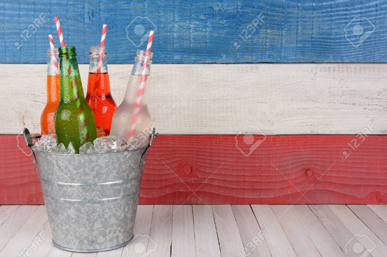 A bucket of soda bottles with drinking straws against a red, white and blue background for a 4th of July picnic, with copy space. - 39041525 A bucket of soda bottles with drinking straws against a red, white and blue background for a 4th of July picnic, with copy space. - 39041525