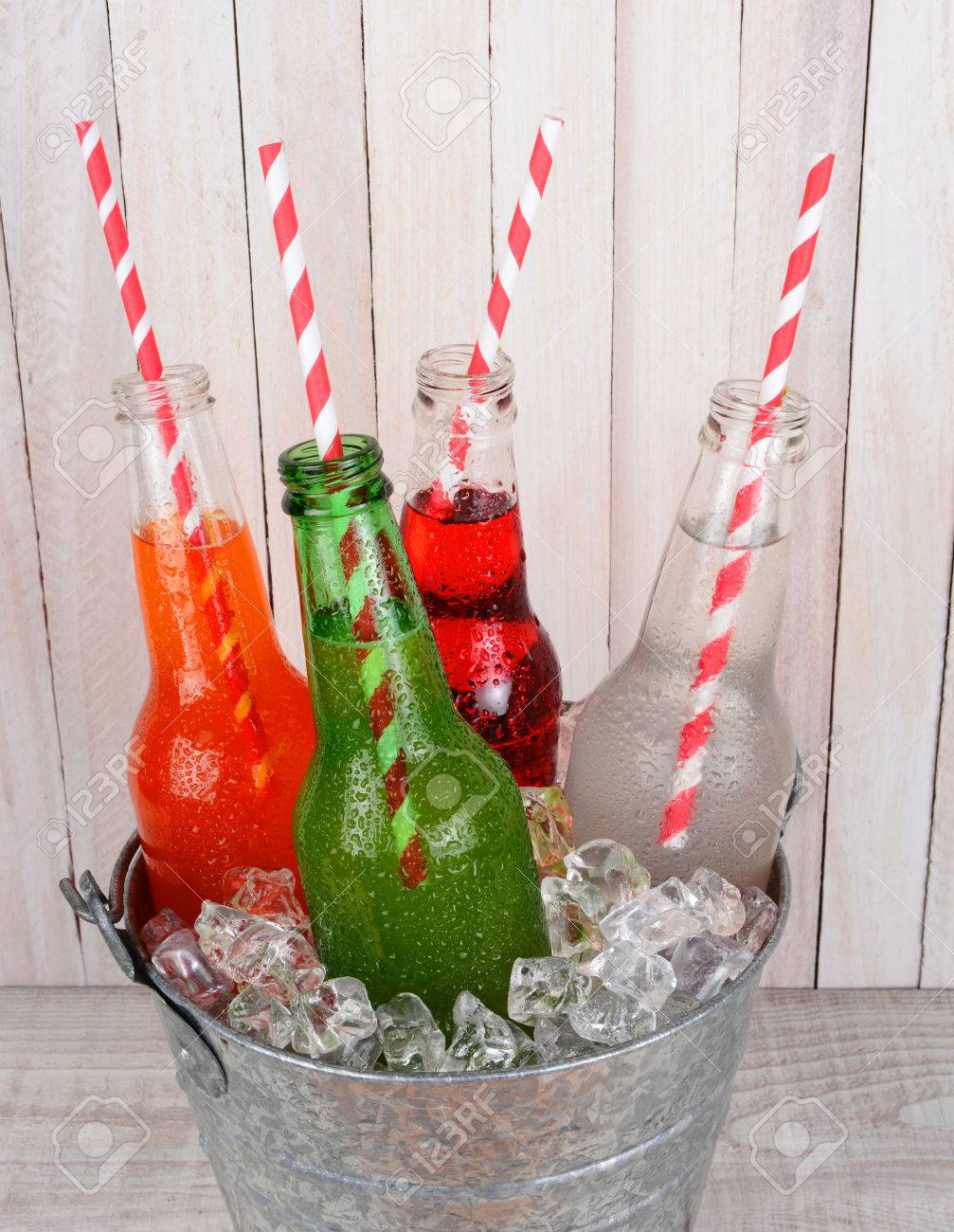 ペットボトルの氷バケットのクローズ アップは 素朴な木製ピクニック テーブルの上に高角度から撮影 4 種類はボトルにストローで飲み物を開きます の写真素材 画像素材 Image