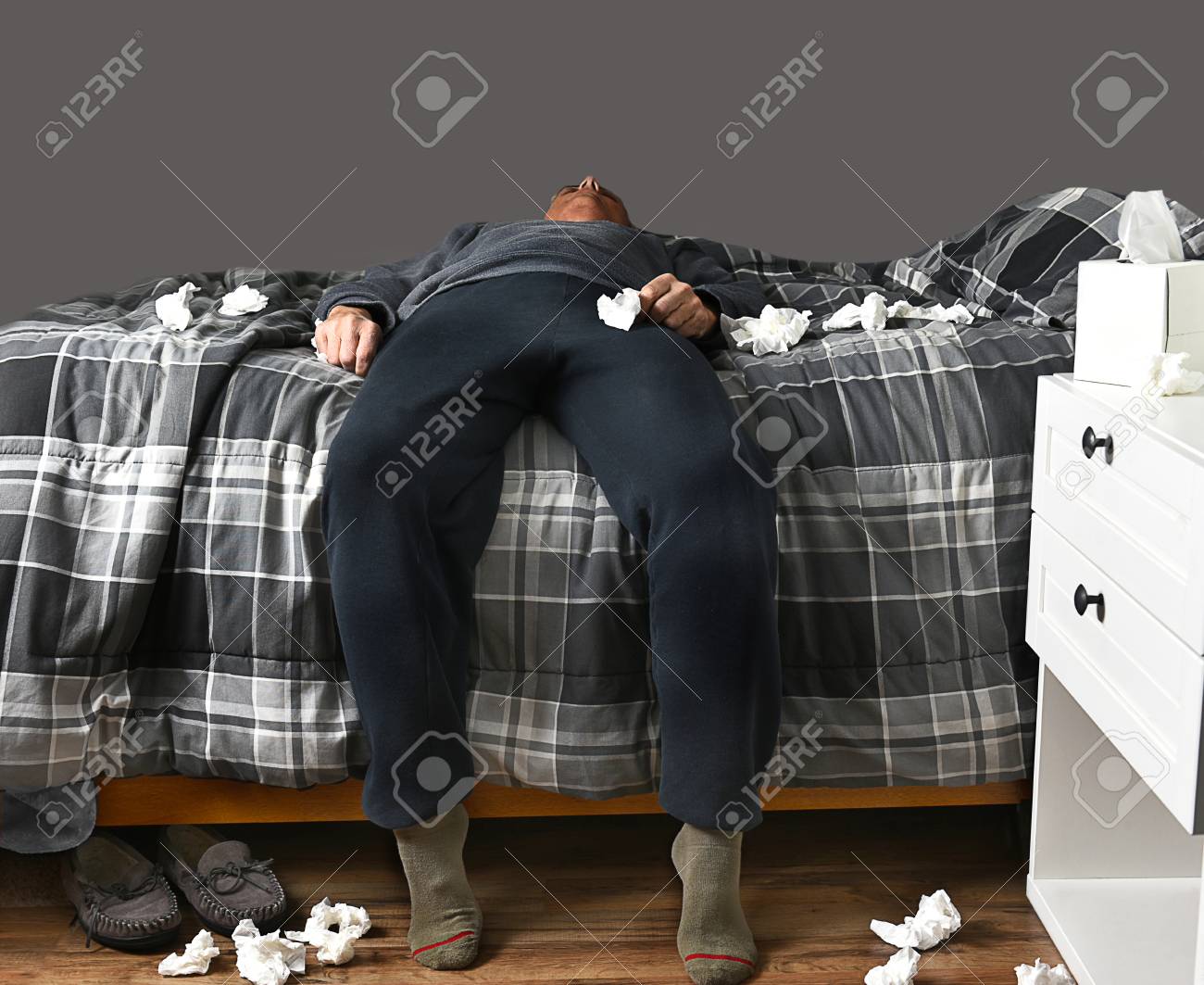 94891543-closeup-of-a-man-laying-across-his-bed-with-feet-on-the-floor-sick-with-the-flu-unable-to-get-up-to-.jpg
