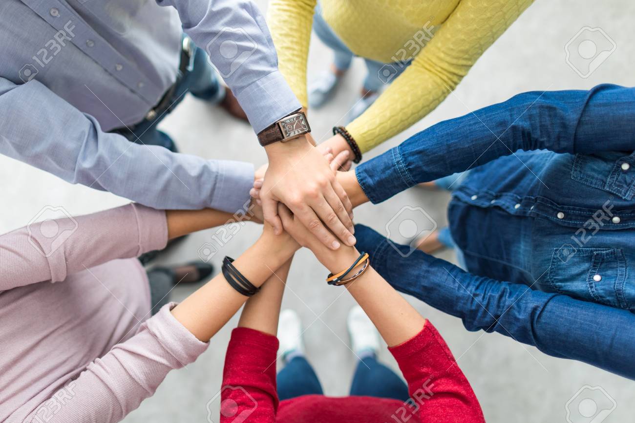 Close up top view of young business people putting their hands together. Stack of hands. Unity and teamwork concept. - 106058173 Close up top view of young business people putting their hands together. Stack of hands. Unity and teamwork concept. - 106058173