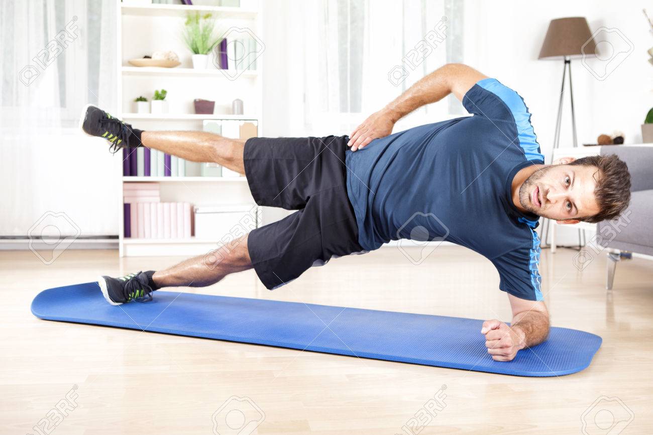 Full Length Shot of a Handsome Athletic Man Doing Side Plank Exercise with One Leg Raised, Looking at the Camera. - 51546205 Full Length Shot of a Handsome Athletic Man Doing Side Plank Exercise with One Leg Raised, Looking at the Camera. - 51546205
