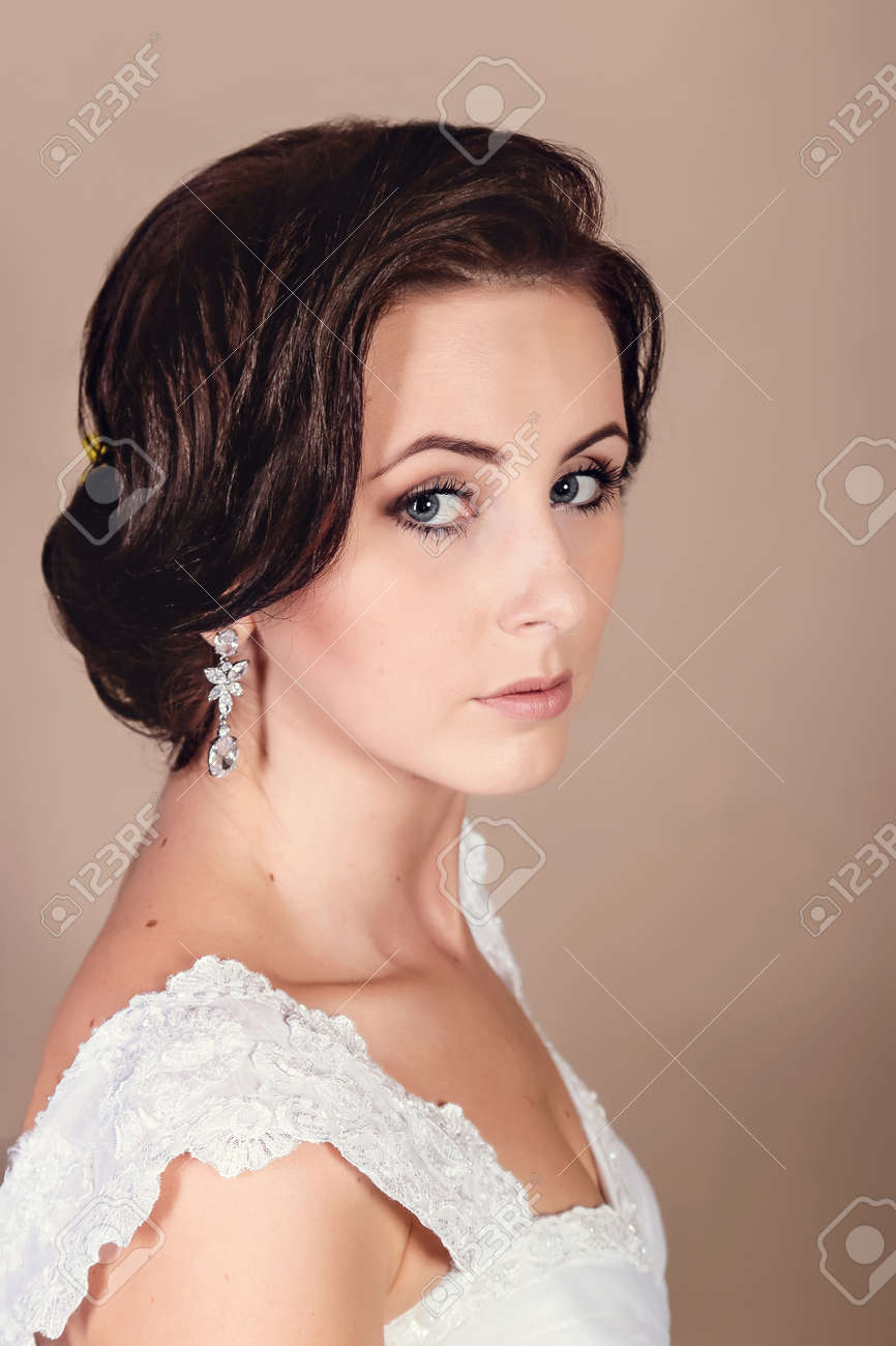 Beautiful bride posing in her wedding day in studio on a beige background. Happy girl holding a basket with a bouquet of tulips - 146686850 Beautiful bride posing in her wedding day in studio on a beige background. Happy girl holding a basket with a bouquet of tulips - 146686850