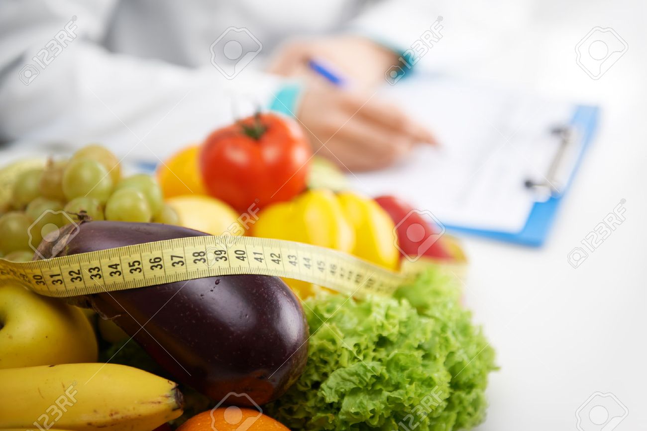 Healthy nutrition concept. Close-up of fresh vegetables and fruits with measuring tape lying on doctor's desk. - 48595947 Healthy nutrition concept. Close-up of fresh vegetables and fruits with measuring tape lying on doctor's desk. - 48595947