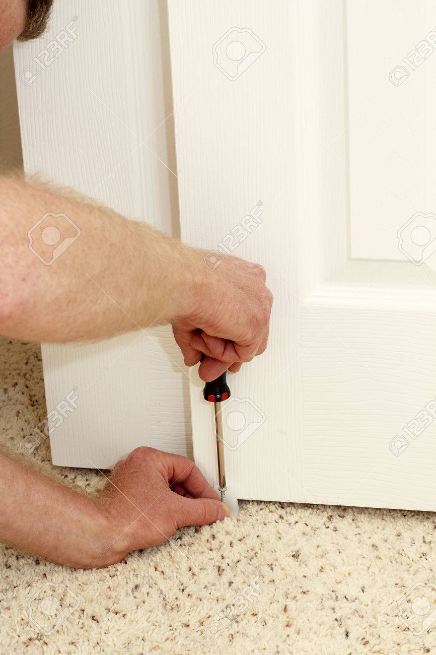 Caucasian Male Using A Screwdriver To Screw In A Bypass Door