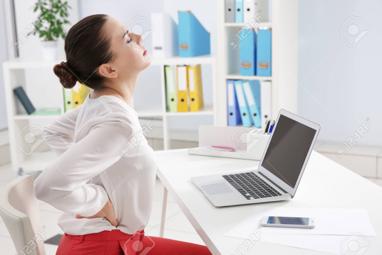 Incorrect posture concept. Young woman with back pain sitting at table in modern room - 110175781 Incorrect posture concept. Young woman with back pain sitting at table in modern room - 110175781