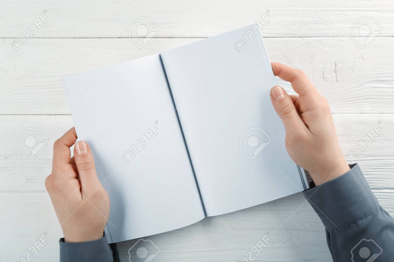 female hands holding blank brochure on wooden background stock photo