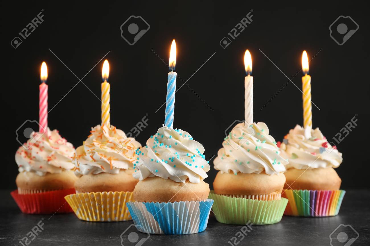 Birthday Cupcakes With Candles On Table Against Black Background