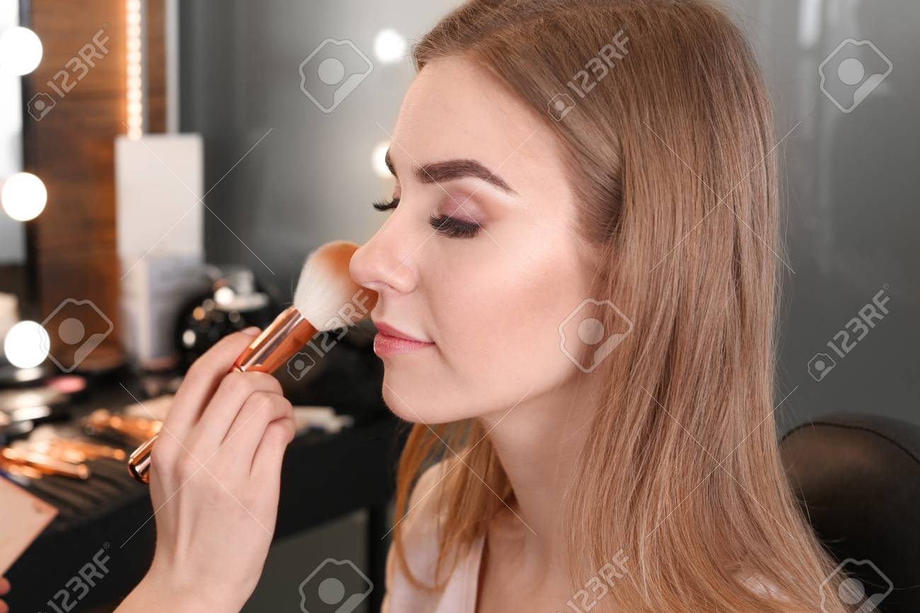 Professional Makeup Artist Applying Makeup On Face Of Young Woman
