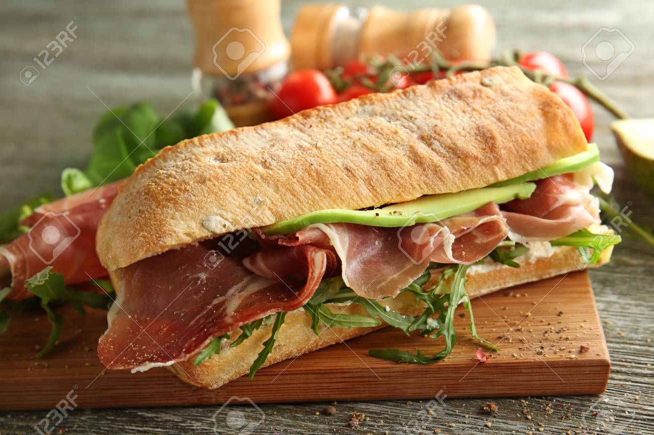 Tasty sandwich with prosciutto on wooden board, closeup - 114618355 Tasty sandwich with prosciutto on wooden board, closeup - 114618355