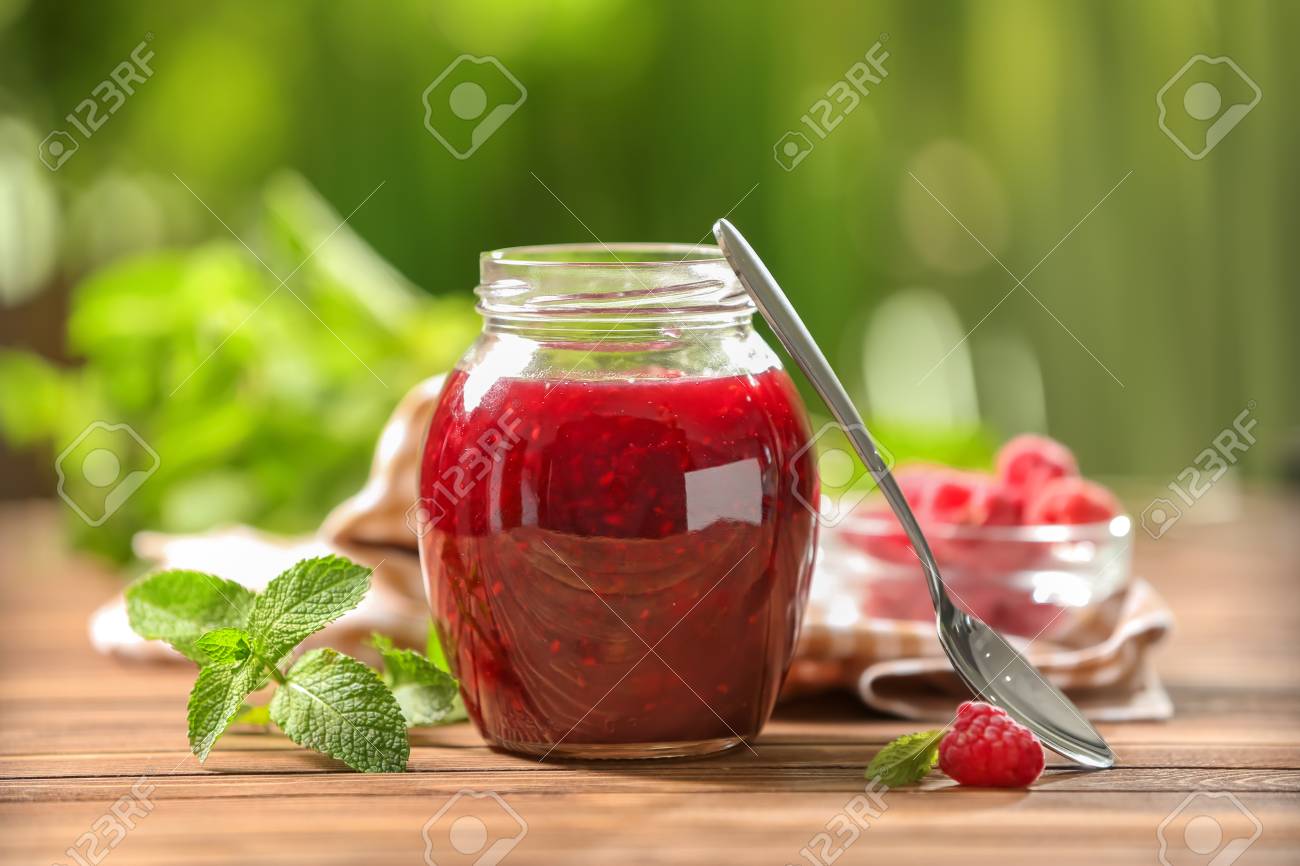 Glass jar with sweet raspberry jam on table outdoors - 114600748 Glass jar with sweet raspberry jam on table outdoors - 114600748
