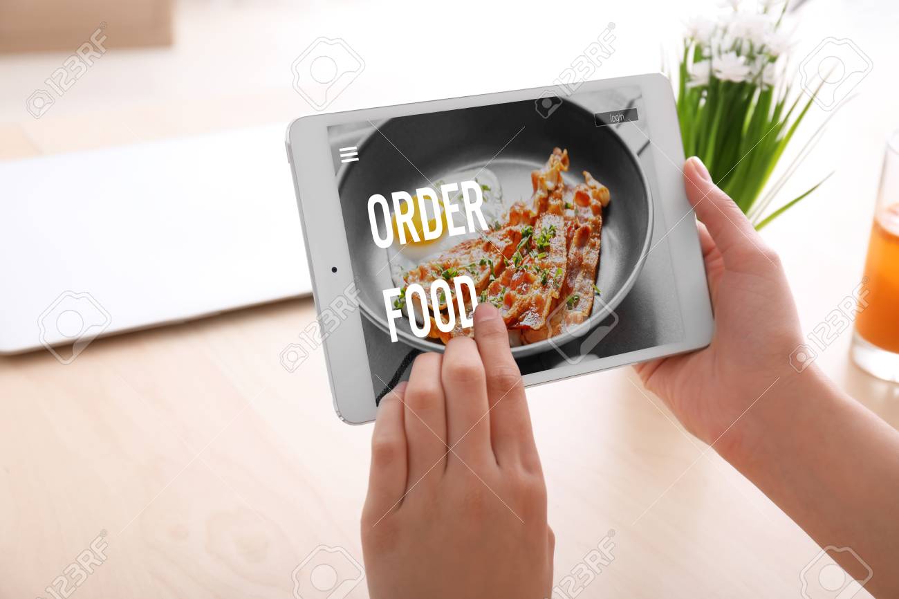 Woman using tablet computer to order food delivery online in office - 115864064 Woman using tablet computer to order food delivery online in office - 115864064