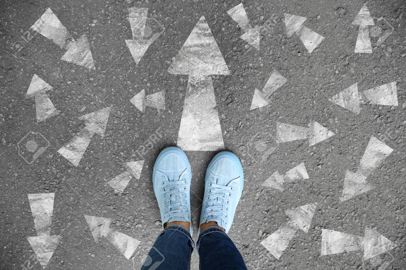 Woman standing on asphalt road with arrows pointing in different directions. Concept of choice - 115394711 Woman standing on asphalt road with arrows pointing in different directions. Concept of choice - 115394711