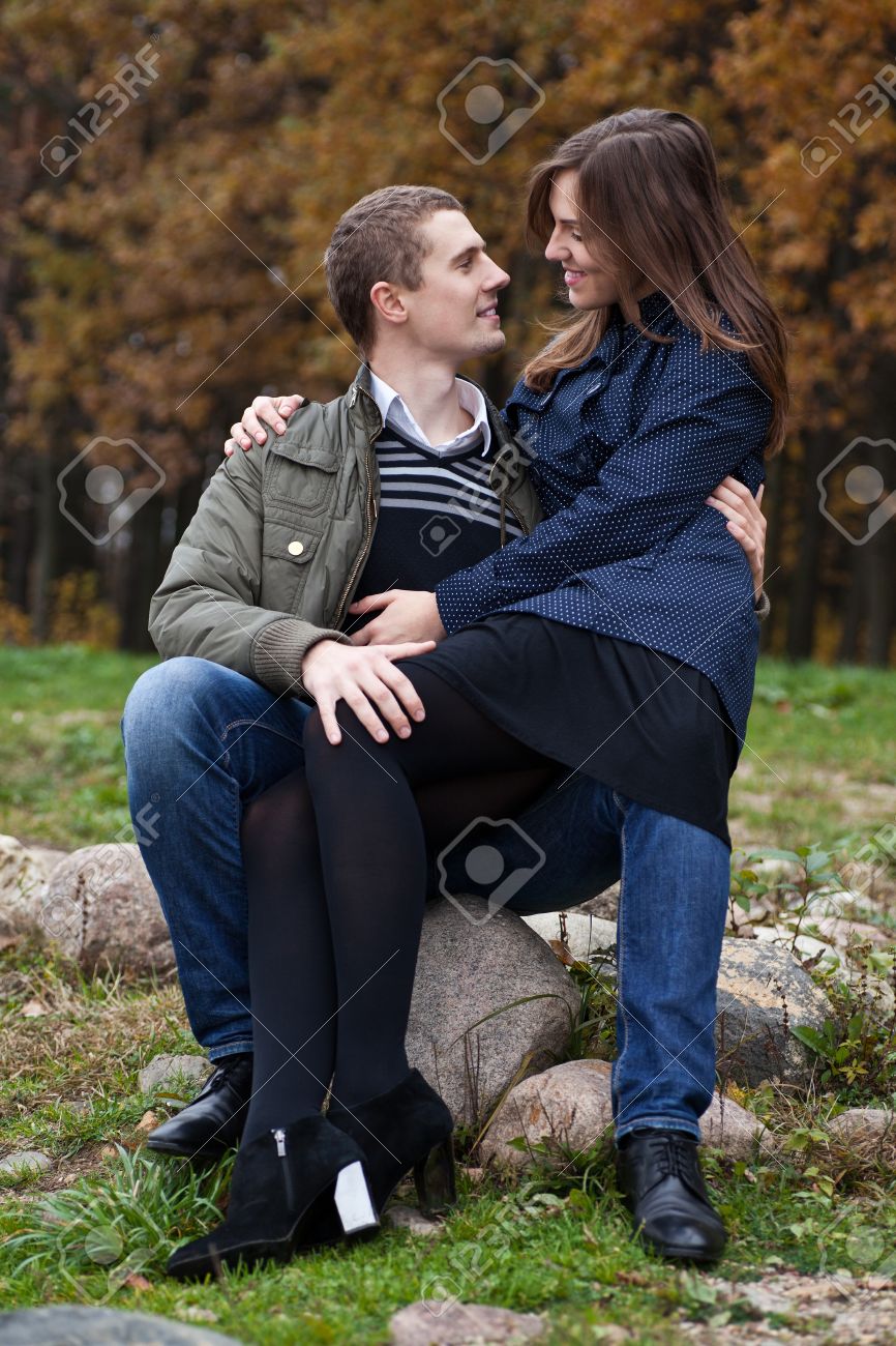 парень целует девушку на лавке. любовь к ребенку. Sitting on lap. женщина сидит на коленях. мальчик сидит на коленях у взрослого.