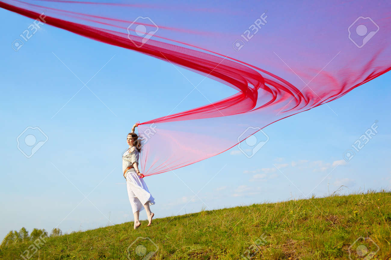 青空の下で赤い光布の大きなピースに走る美しいヒッピー女の子の屋外のポートレート の写真素材 画像素材 Image