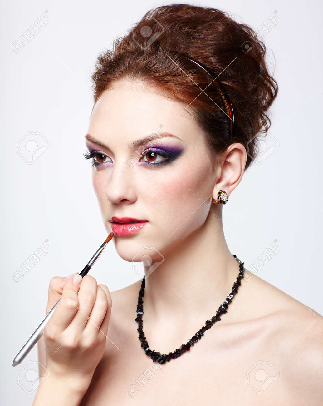 ブラシに口紅を置くのメーキャップ アーティストの手によるしゃれ若くてきれいな女性の肖像画 の写真素材 画像素材 Image