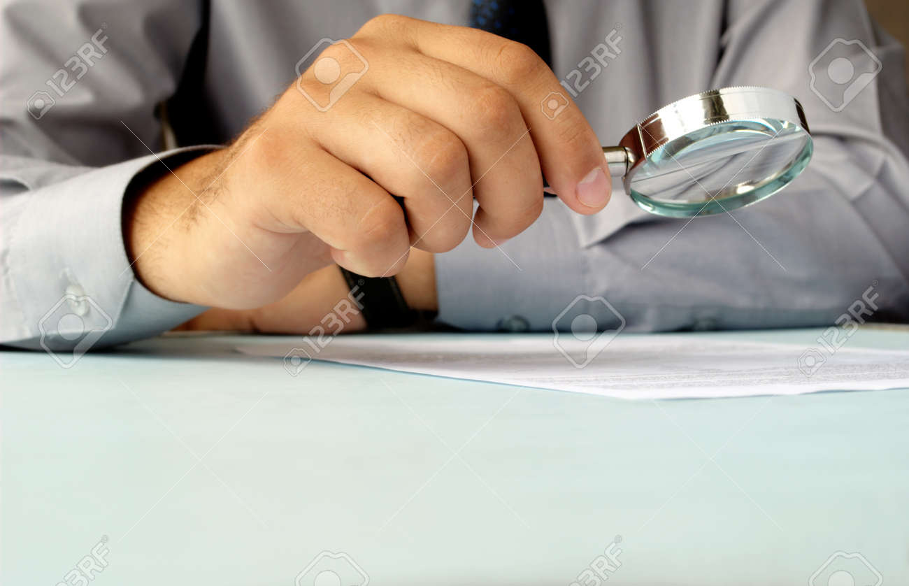 Businessman looking through a magnifying glass to documents - 14866993 Businessman looking through a magnifying glass to documents - 14866993