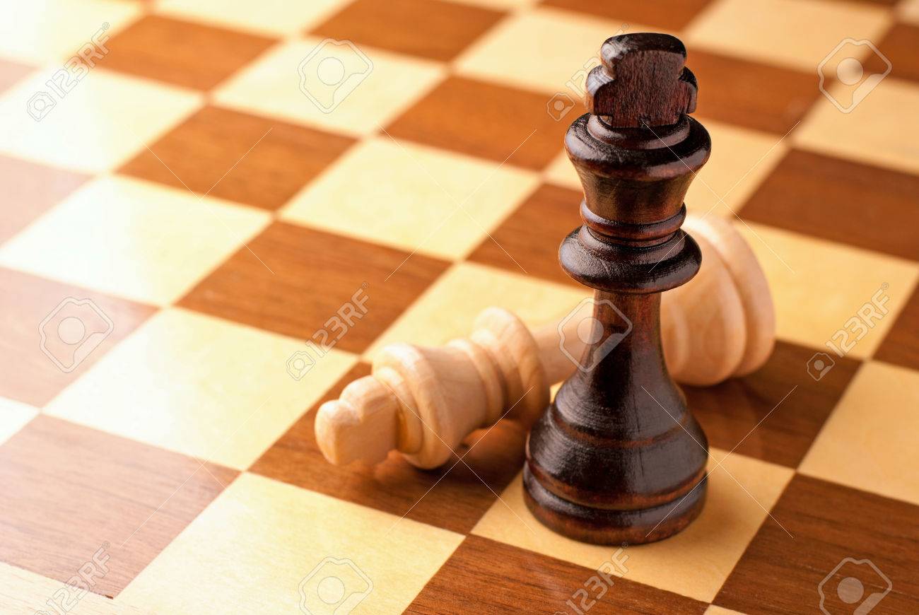 Two King chess pieces on a chessboard with the light king lying on its side at the foot of the victorious dark wood King Stock Photo - Alamy