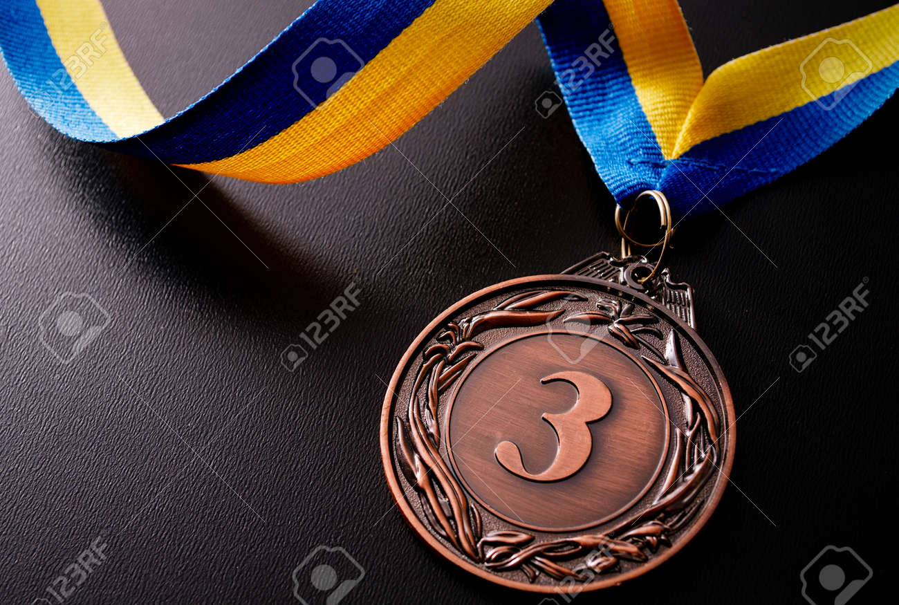 Bronze medal in the foreground on yellow blue ribbon - 36510632 Bronze medal in the foreground on yellow blue ribbon - 36510632