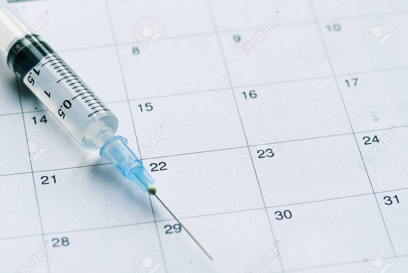 Medical syringe with transparent vaccine on white calendar background. Vaccination schedule concept with copy space - 134138204 Medical syringe with transparent vaccine on white calendar background. Vaccination schedule concept with copy space - 134138204