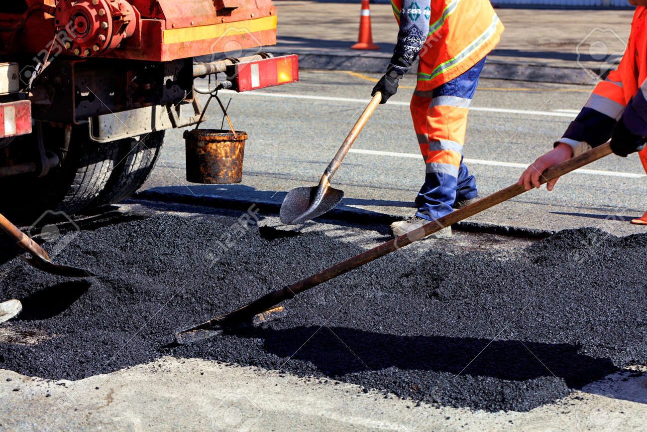 The road workers' working group renews a part of the road with fresh asphalt and levels it for repair in road construction. - 123739829 The road workers' working group renews a part of the road with fresh asphalt and levels it for repair in road construction. - 123739829