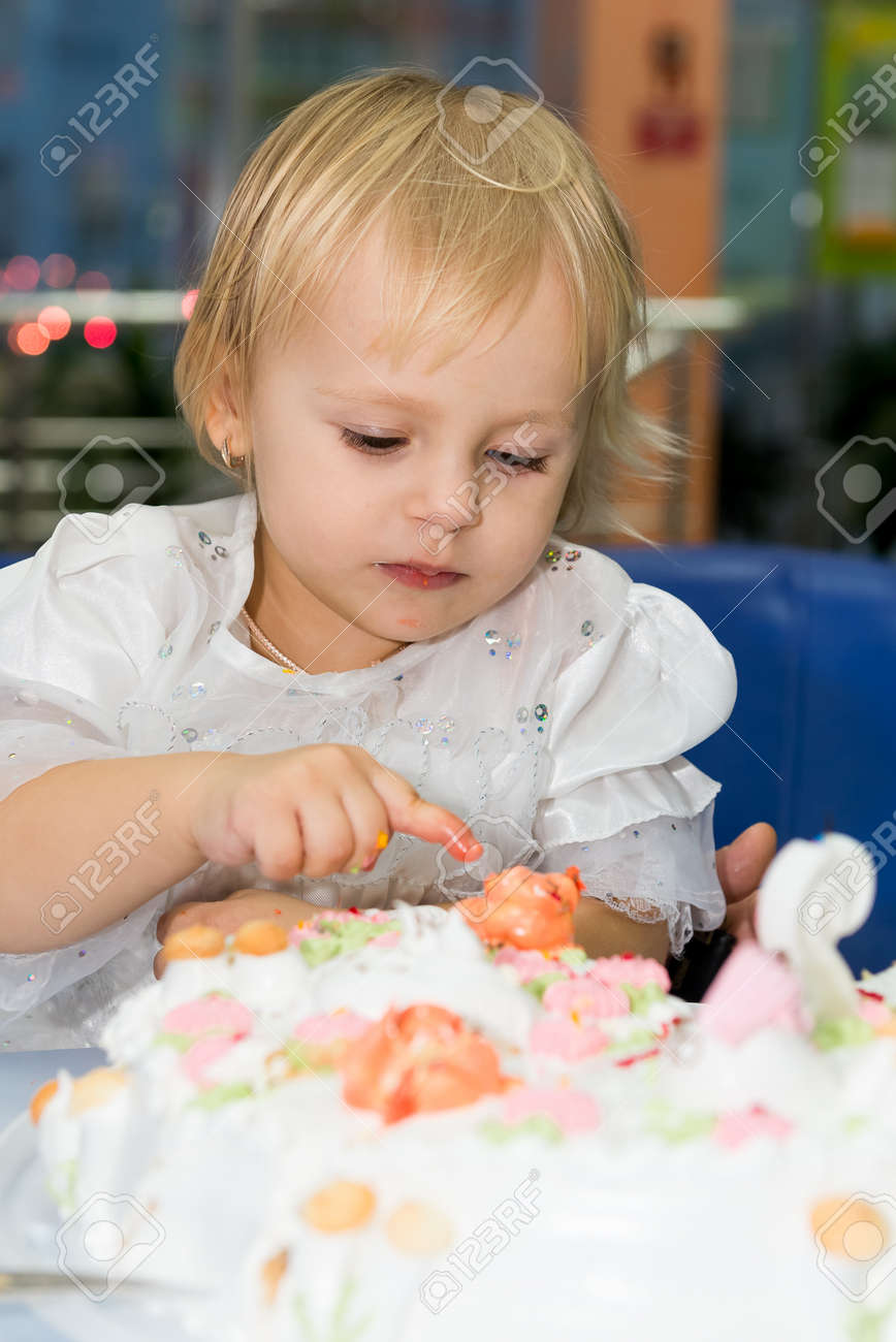 幸せな少女は 彼の誕生日にバースデー ケーキのろうそくを吹きます 子供は 誕生日ケーキに指クリームを食べる の写真素材 画像素材 Image