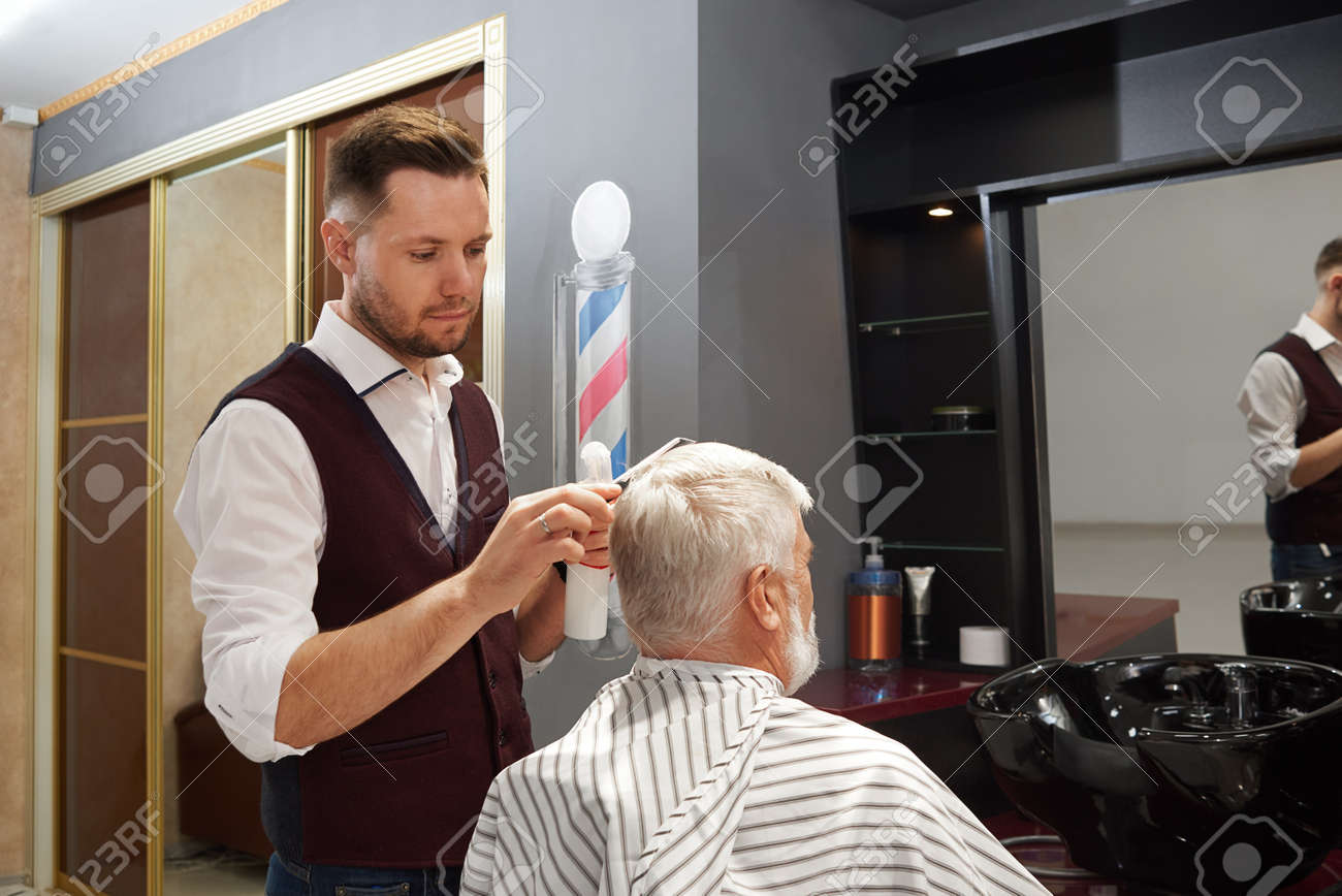Man With Grey Hair Sitting In Chair In Haircut Gown And Having