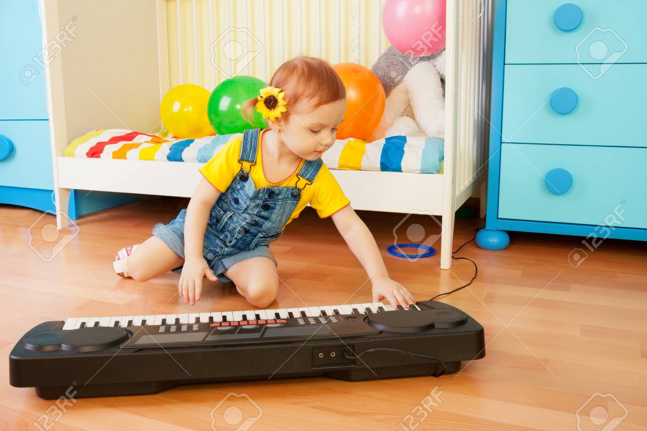 Girl Playing Piano Sitting On The Floor In Bedroom Stock Photo