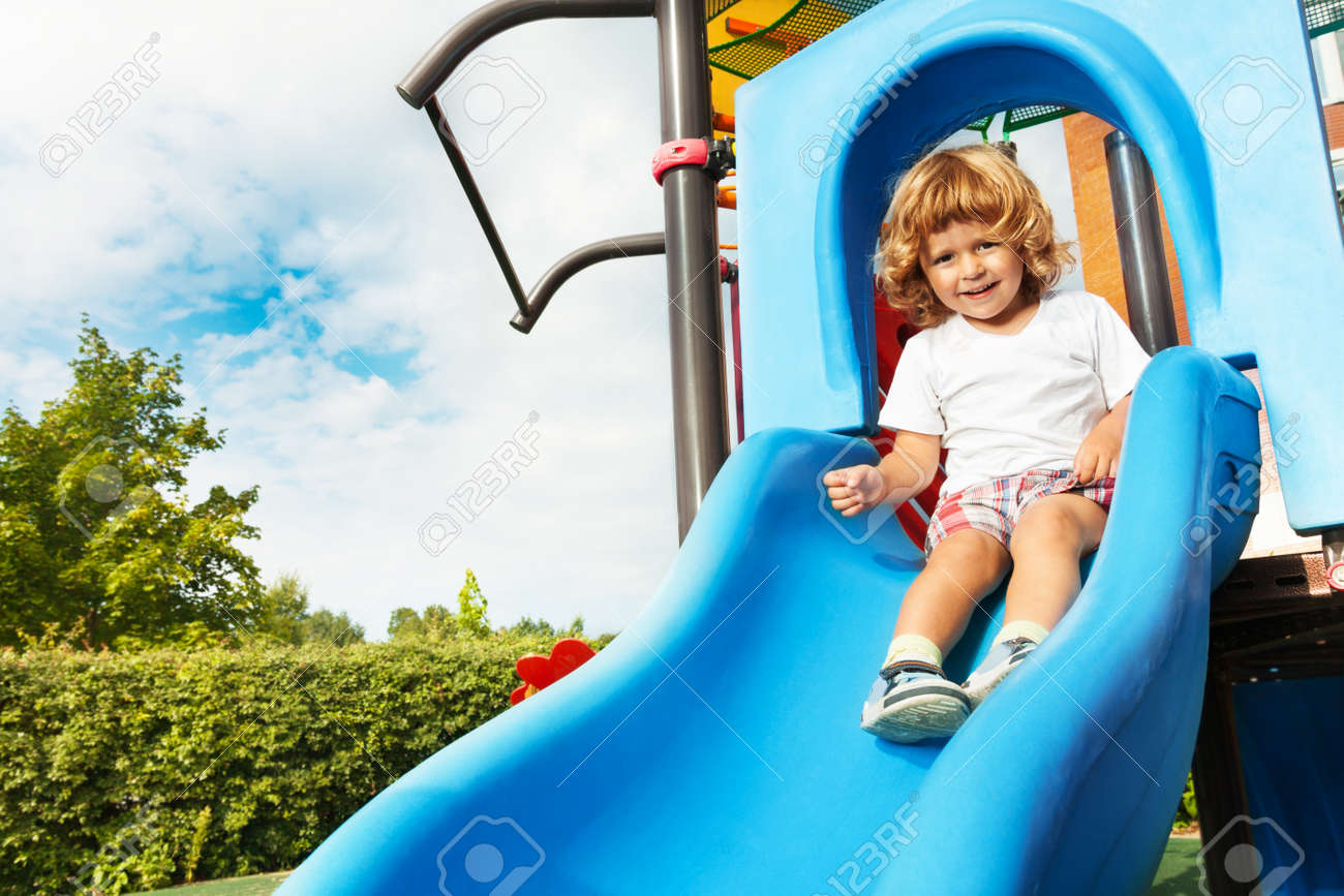 幸せな笑みを浮かべて 3 歳坊や青い遊び場スライドしよう の写真素材 画像素材 Image