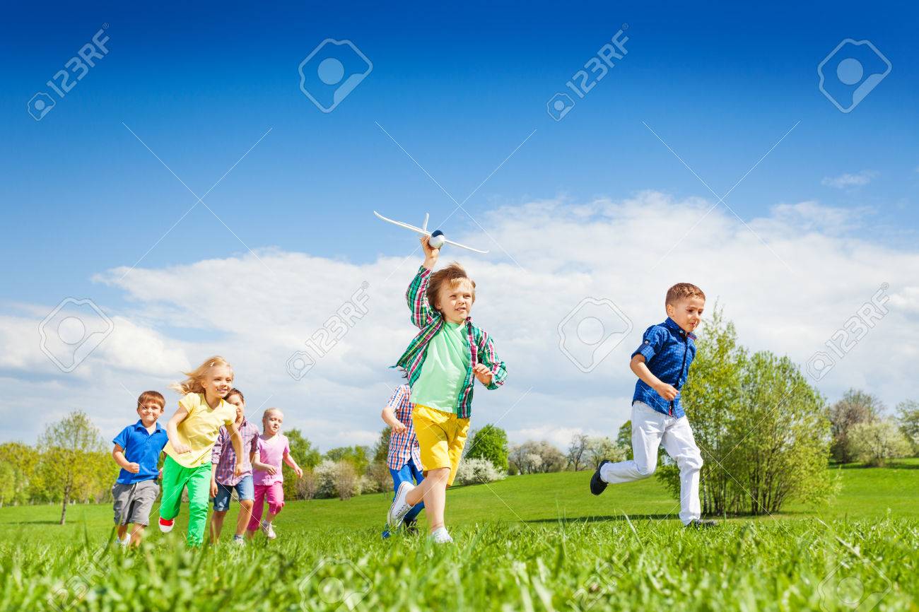running boy with airplane toy and other children running happily