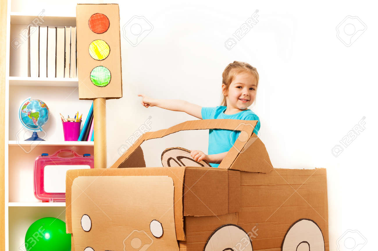 彼女の指でグッズの信号を指している手作りダン ボール車のホイールで 4 歳の女の子の笑顔 の写真素材 画像素材 Image