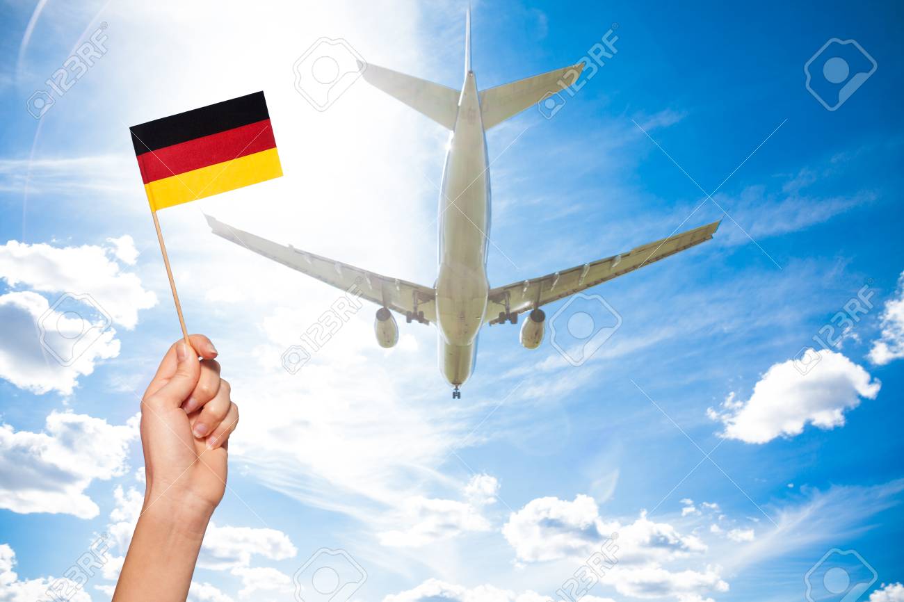 german flag against airplane flying through sky stock photo picture