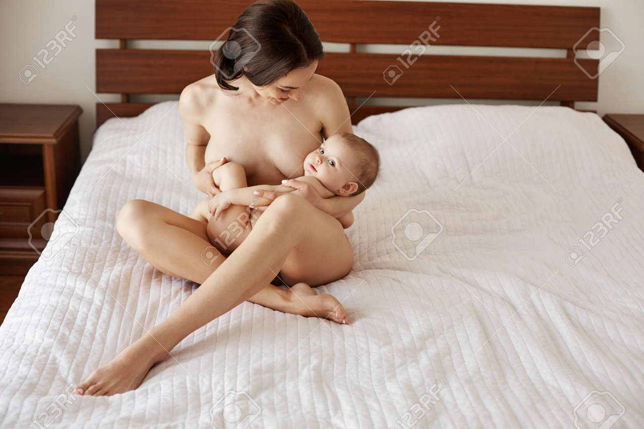 Joven Y Atractiva Madre Desnuda Amamantando Abrazando A Su Bebé Recién  Nacido Sonriendo Sentado En La Cama En Su Casa. Fotos, retratos, imágenes y  fotografía de archivo libres de derecho. Image 81201236