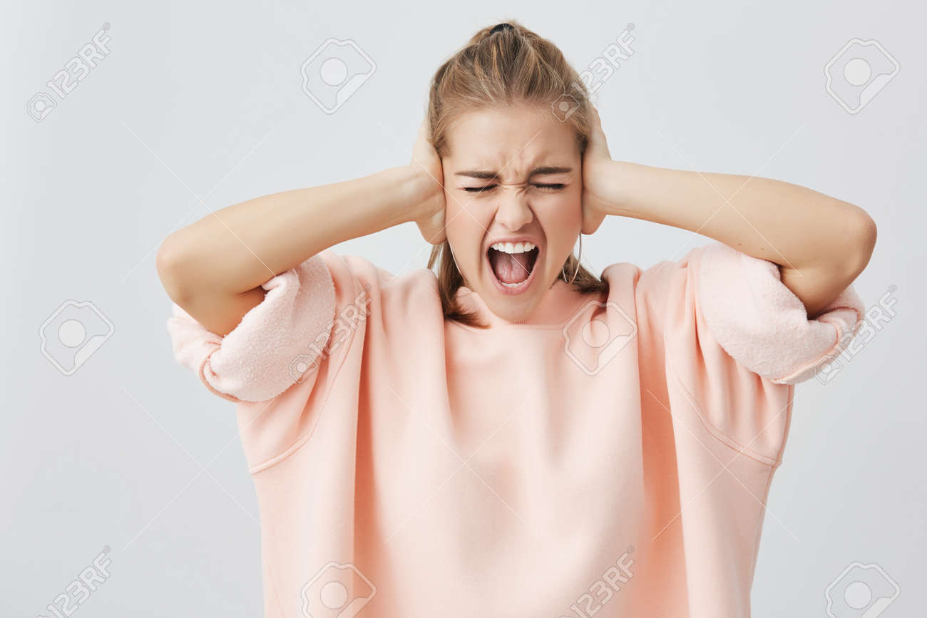 感情的な叫び口を開けて 若い白人女性を絶望し 悲鳴 悪いニュースを聞くことを拒否として彼女の耳を閉じて目を閉じ 顔の表情 反応 否定的な感情 の写真素材 画像素材 Image