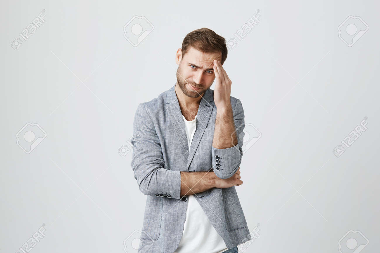 トレンディな服を着たイライラした白人男性は 騒音のために顔をしかめ 痛みのために額に手を握った 否定的な感情 ストレス頭痛や欲求不満 の写真素材 画像素材 Image