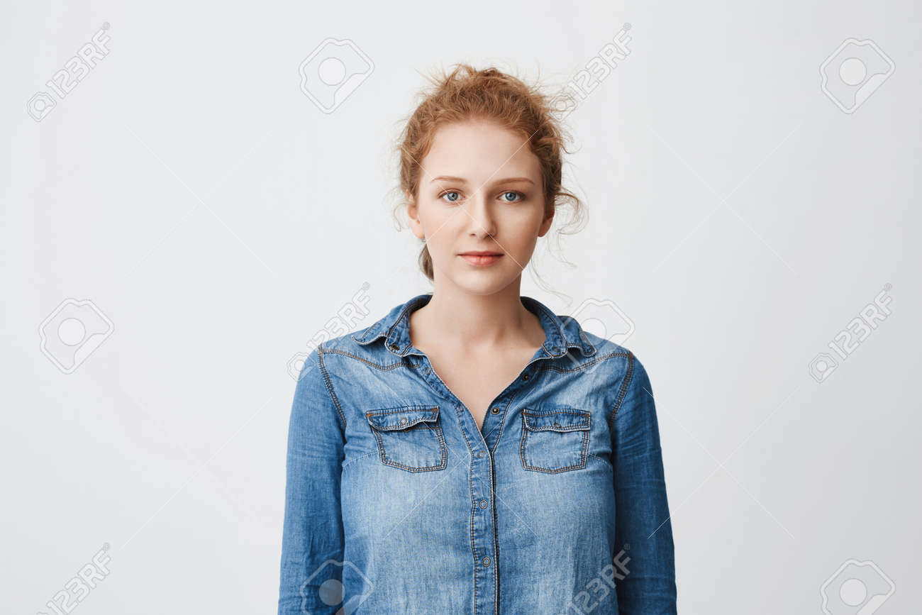 髪をくしゃくしゃにしたかわいい10代のジンジャーガールと グレーの背景にデニムシャツを着て立つ美しい青い目で 落ち着いたリラックスした気分を表現しています 学生は彼女の順番が試験に合格するのを待ちます の写真素材 画像素材 Image