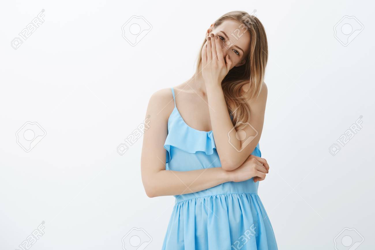 Funny Enthusiastic Girl Chuckling, Laughing Over Brother Tilting Head  Covering Mouth With Palm Having Fun And Fooling Around, Wearing Elegant  Blue Dress Posing Amused Against Grey Wall Stock Photo, Picture and Royalty, image size:1300x866
