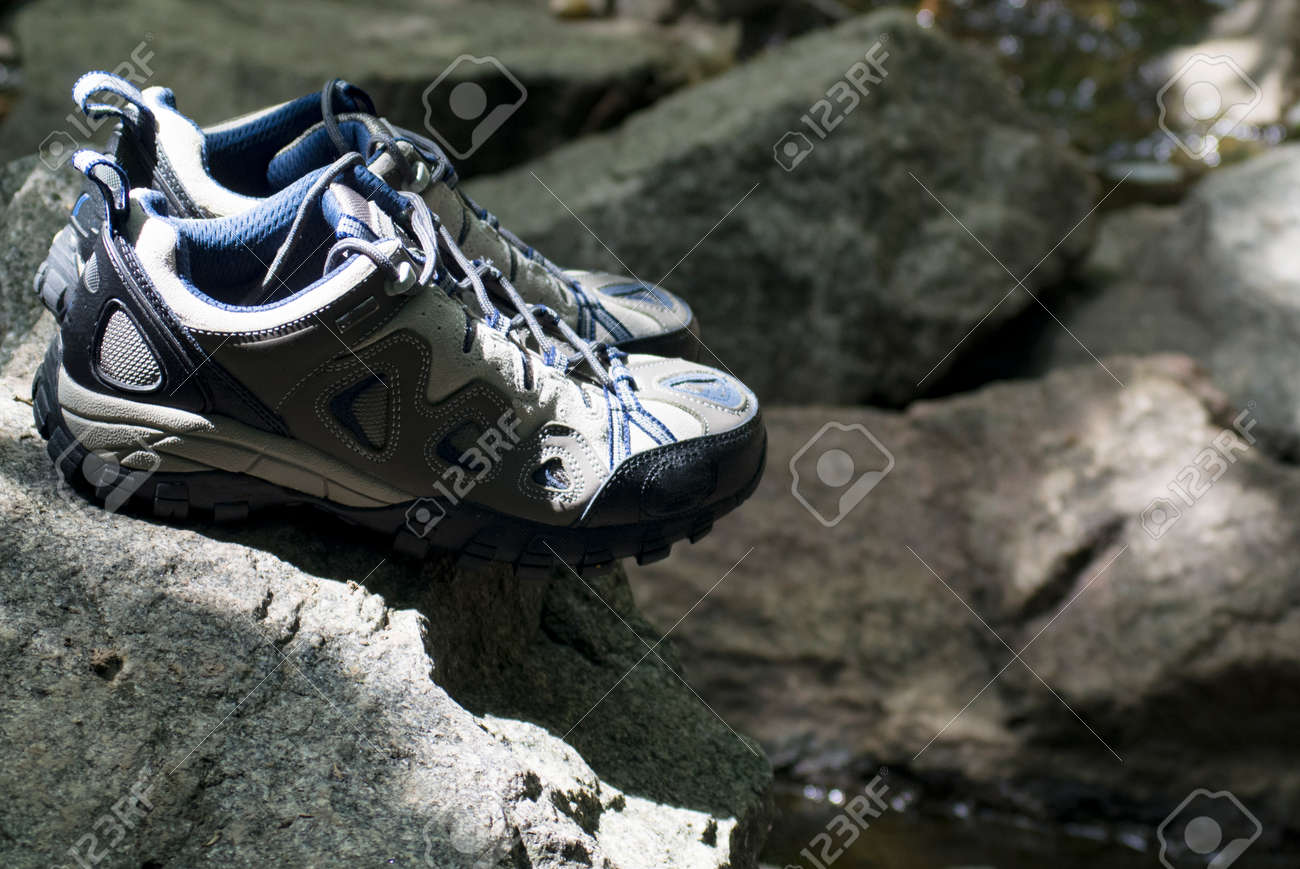 A pair of hiking shoes stand on granite stones - 159935637 A pair of hiking shoes stand on granite stones - 159935637