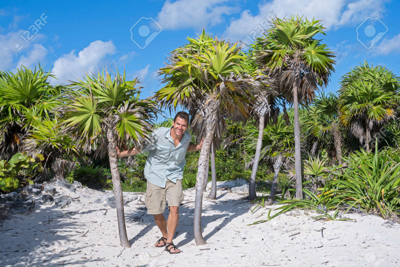 笑みを浮かべて冒険白人男は間 2 つのヤシの木 メキシコのカンクン近くのビーチを探索しながら歩く の写真素材 画像素材 Image