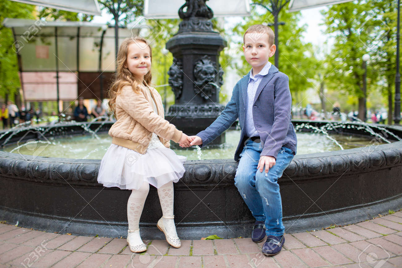 Boy Holding Girl S Hand Children Sitting At The Fountain Outdoor Stock Photo Picture And Royalty Free Image Image