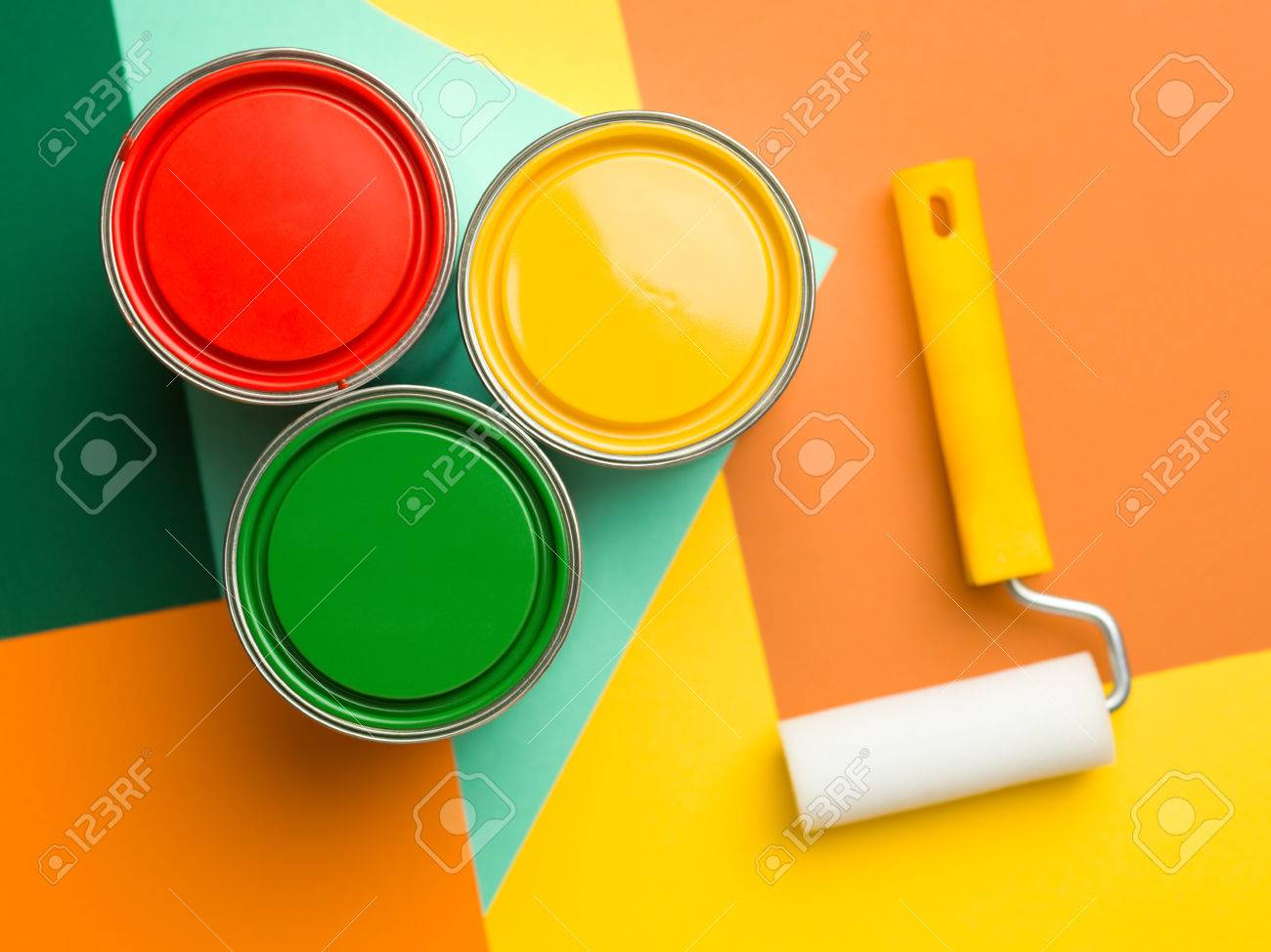 three cans yellow green and red and paint roll on colourful stock