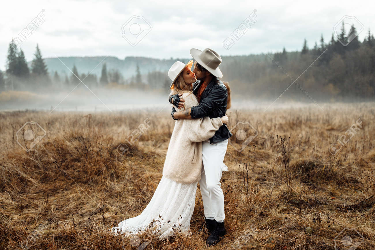 Lovely Couple Posing At The Field, Attractive Bride Hug Handsome Groom,  Charming Man And Beautiful Woman Look At The Camera, Enjoy Happy Marriage,  Wedding Photoshoot Concept. High Quality Photo Stock Photo, Picture, image size:1300x867