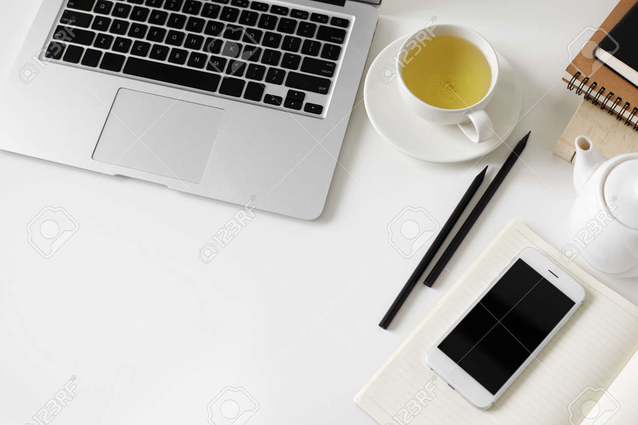 stock photo top view on modern office desk of creative designer workspace with laptop books and notepad cup green tea mobile phone on diary pencils
